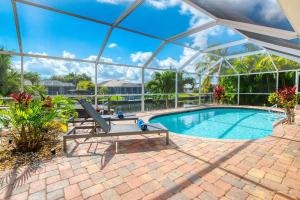 a swimming pool with a bench and an umbrella at Casa Nalani - phenomenal 8 guest holiday villa in the Yacht Club in Cape Coral