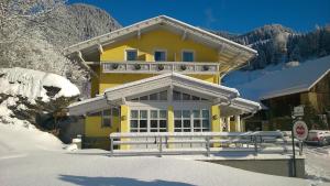 a yellow house with a fence in the snow at Pension Siegelbrunn B&B in Mallnitz