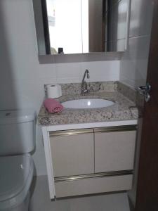 a bathroom with a sink and a toilet and a mirror at Jurerê Spécial Atlântico in Florianópolis
