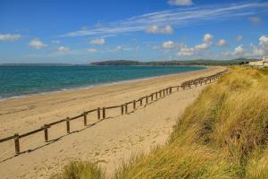 a sandy beach with a fence and the ocean at Ynata in Caernarfon