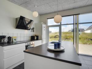 uma cozinha com armários brancos e um balcão preto em Holiday Home Julika - 400m from the sea in NW Jutland by Interhome em Torsted