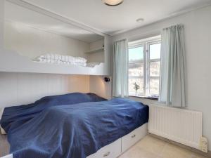 ein Schlafzimmer mit einem Bett mit einer blauen Decke in der Unterkunft Holiday Home Tabea - 150m from the sea in NW Jutland by Interhome in Løkken