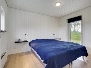 1 dormitorio con 1 cama azul en una habitación con ventana en Holiday Home Øthbiorn - 1-1km from the sea in NW Jutland by Interhome en Løkken