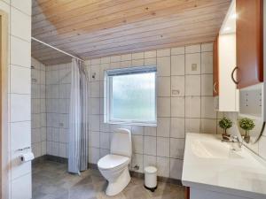 a bathroom with a toilet and a sink and a window at Holiday Home Anegrete - 900m from the sea in NW Jutland by Interhome in Torsted