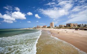 een strand met mensen in het water en gebouwen bij Bush 2 Beach Inn in Summerstrand