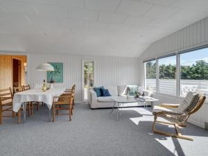 ein Wohnzimmer mit einem Sofa, einem Tisch und Stühlen in der Unterkunft Holiday Home Kanerva - 350m from the sea in NW Jutland by Interhome in Torsted