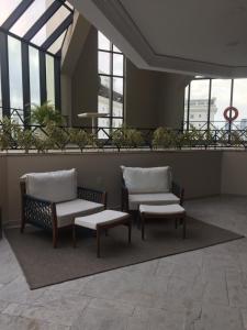 2 sillas y un banco en un edificio con ventanas en Oscar Freire Jardins SP, en São Paulo