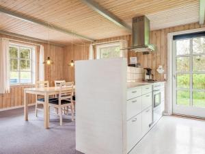 eine Küche mit einem Tisch und einem weißen Kühlschrank in der Unterkunft Holiday Home Nanja - 759m from the sea in NW Jutland by Interhome in Løkken