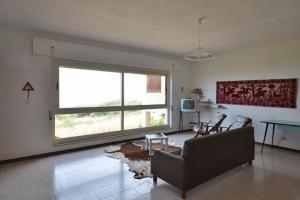 uma sala de estar com um sofá e uma grande janela em Appartamenti Salusai em Trinità d'Agultu e Vignola