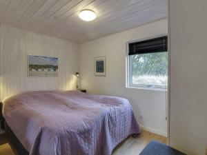 um quarto com uma cama com um cobertor roxo e uma janela em Holiday Home Grit - 650m from the sea in NW Jutland by Interhome em Lokken