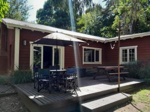 una terraza con mesa, sillas y sombrilla en Cabaña Sueca, en Mar del Plata