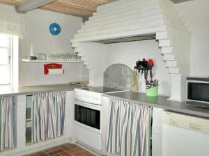 uma cozinha com armários brancos e um forno com placa de fogão em Holiday Home Genta - 100m from the sea in NW Jutland by Interhome em Lokken