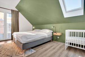 a green bedroom with a bed and a crib at Mirabel Apartments Klinovec in Loučná pod Klínovcem
