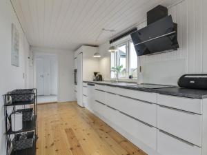 a kitchen with white cabinets and a wooden floor at Holiday Home Nehat - 300m from the sea in NW Jutland by Interhome in Løkken