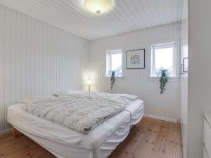 a white bedroom with a large bed and two windows at Holiday Home Nehat - 300m from the sea in NW Jutland by Interhome in Løkken