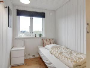 a white bedroom with a bed and a window at Holiday Home Nehat - 300m from the sea in NW Jutland by Interhome in Løkken