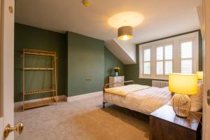 a bedroom with green walls and a bed with a lamp at Harrogate Victorian Luxury in Harrogate