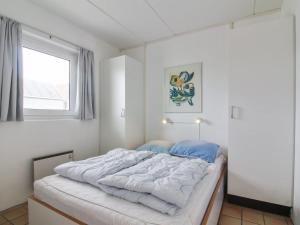 um quarto com uma grande cama branca e uma janela em Apartment Tinke - 150m from the sea in NW Jutland by Interhome em Lokken