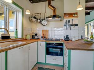 uma cozinha com armários brancos e um forno azul em Holiday Home Quirina - 75m from the sea in NW Jutland by Interhome em Torsted