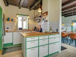 uma cozinha com armários verdes e brancos e uma mesa em Holiday Home Quirina - 75m from the sea in NW Jutland by Interhome em Torsted