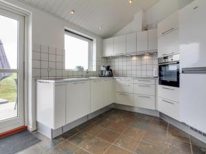een keuken met witte kasten en een groot raam bij Holiday Home Senni - 1-1km from the sea in NW Jutland by Interhome in Løkken