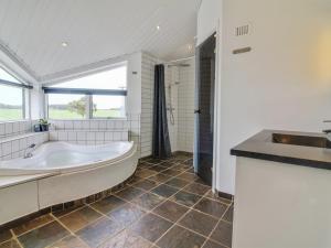 een witte badkamer met een bad en een wastafel bij Holiday Home Senni - 1-1km from the sea in NW Jutland by Interhome in Løkken