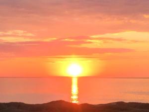 einen Sonnenuntergang über dem Wasser mit der Sonne am Himmel in der Unterkunft Holiday Home Alyssa - 300m from the sea in NW Jutland by Interhome in Løkken