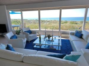 ein Wohnzimmer mit weißen Sofas und einem Glastisch in der Unterkunft Holiday Home Alyssa - 300m from the sea in NW Jutland by Interhome in Løkken