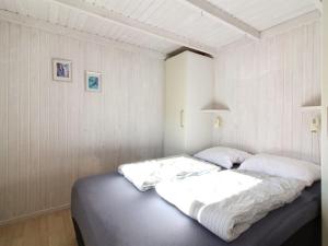 un letto in una camera con pareti bianche di Holiday Home Aponi - 400m from the sea in NW Jutland by Interhome a Løkken