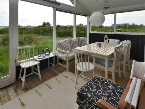 een veranda met een tafel, stoelen en ramen bij Holiday Home Jerker - 400m from the sea in NW Jutland by Interhome in Løkken