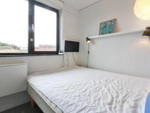 een wit bed in een kamer met een raam bij Holiday Home Mielikki - 200m from the sea in NW Jutland by Interhome in Løkken