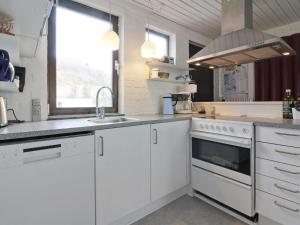 een keuken met witte kasten, een wastafel en een fornuis bij Holiday Home Mielikki - 200m from the sea in NW Jutland by Interhome in Løkken