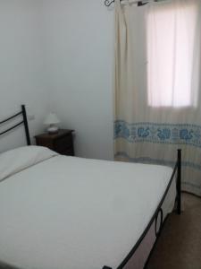 Una cama blanca en un dormitorio con ventana. en Casa Sara&Chiara, en Santa Margherita di Pula