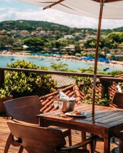 uma mesa de madeira com copos de vinho e um guarda-chuva em Jubarte Hotel by Insólito em Búzios