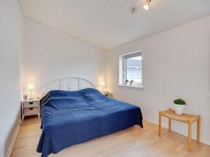 een witte slaapkamer met een blauw bed en een raam bij Apartment Meglena - 50m from the sea in NW Jutland by Interhome in Løkken