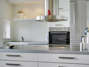 uma cozinha com armários brancos e um forno com placa de fogão em Holiday Home Oliver - 600m from the sea in NW Jutland by Interhome em Lokken