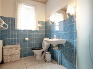 La salle de bains est pourvue de carrelage bleu, de toilettes et d'un lavabo. dans l'établissement Apartment Jördis - 150m from the sea in NW Jutland by Interhome, à Løkken
