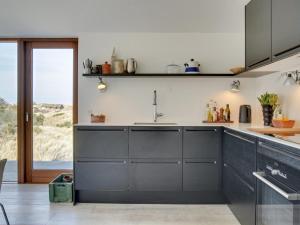 ブロックフスにあるHoliday Home Silvette - 400m from the sea in NW Jutland by Interhomeのキッチン(黒いキャビネット付)、大きな窓