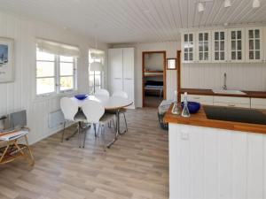 cocina y comedor con mesa y sillas blancas en Holiday Home Adelita - 100m from the sea in NW Jutland by Interhome, en Løkken