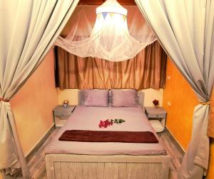 Un dormitorio con una cama con cortinas y flores. en Surfers-Lounge-Dahab Lagoon with Swimming-Pool - Breakfast - Garden - Beduintent - BBQ - Jacuzzi, en Dahab