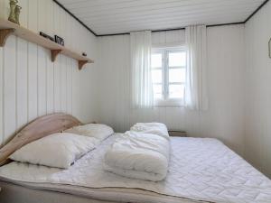 a bed with white sheets and pillows in a room at Holiday Home Demus - 900m from the sea in NW Jutland by Interhome in Løkken