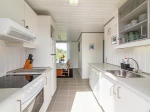 a kitchen with white cabinets and a sink and a table at Holiday Home Demus - 900m from the sea in NW Jutland by Interhome in Løkken