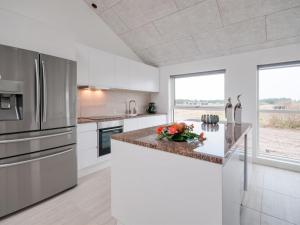 una cocina con armarios blancos y electrodomésticos de acero inoxidable en Holiday Home Eveline - 1-5km from the sea in NW Jutland by Interhome, en Løkken