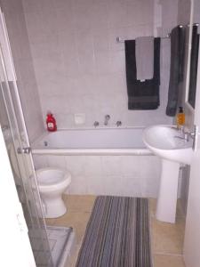 a bathroom with a toilet and a tub and a sink at Gabby's apartment in Cape Town
