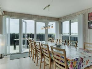 ein Esszimmer mit einem Tisch, Stühlen und Fenstern in der Unterkunft Holiday Home Skamhals - 700m from the sea in NW Jutland by Interhome in Blokhus