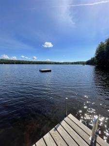 a dock on a lake with a boat in the water at TREMONT LIMIT 10 villa in Bridgton