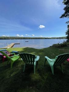 a group of chairs sitting on the grass near a lake at TREMONT LIMIT 10 villa in Bridgton