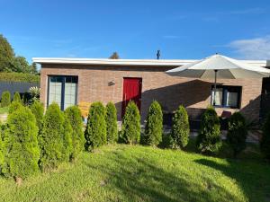 a brick house with a red door and an umbrella at Karolina‘s Deluxe Appartement-Bungalow in Dranske