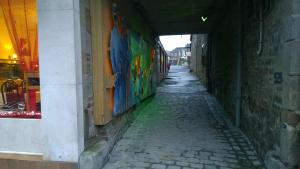 an alley with graffiti on the side of a building at Hôtel Saint - Pierre in Villedieu-les-Poêles
