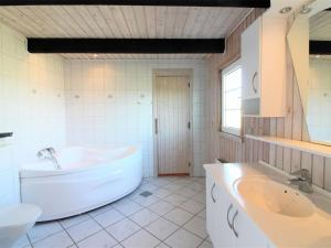 een witte badkamer met een bad en een wastafel bij Holiday Home Arita - 250m from the sea in NW Jutland by Interhome in Saltum